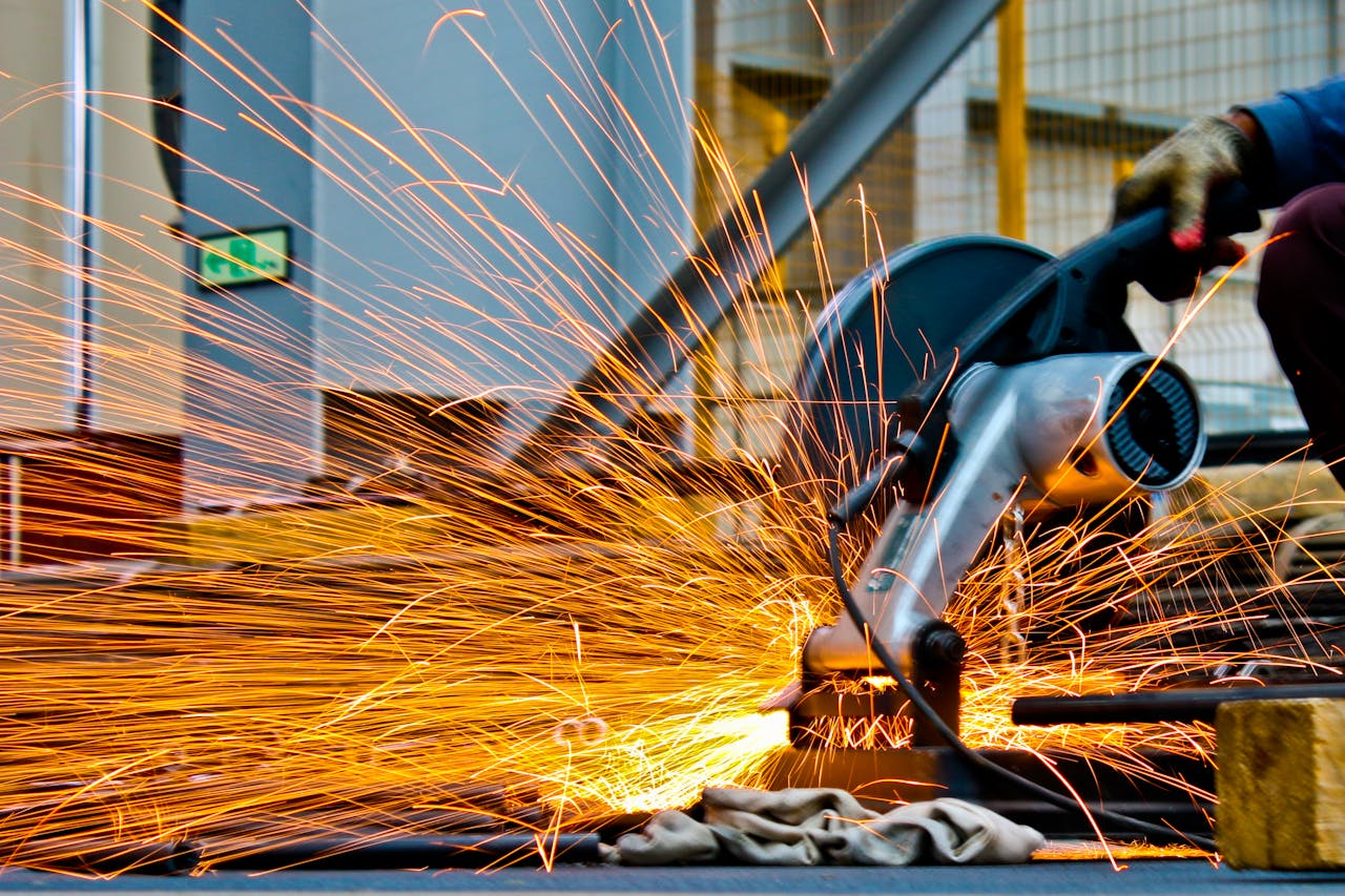 why-choose-us A worker operates a grinder cutting metal, creating a vibrant display of sparks in an industrial setting.