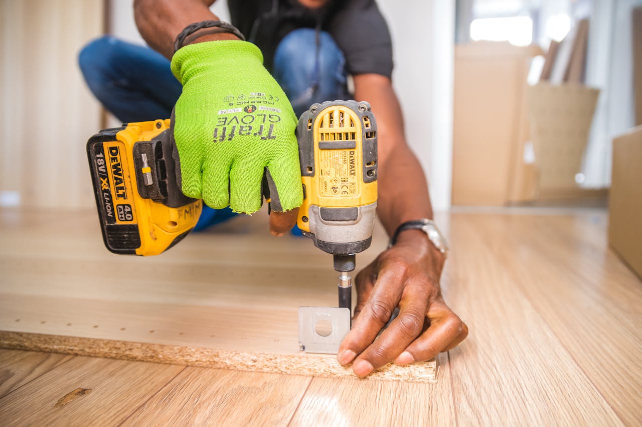 get-in-touch Man using a power drill for home improvement on a wooden floor with precision.