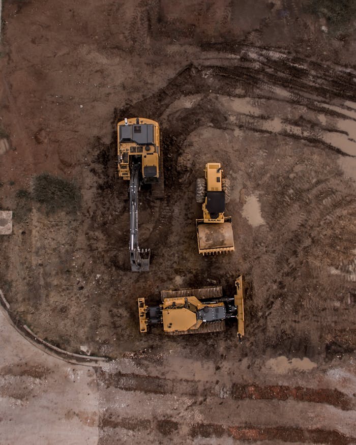 services-04 An aerial shot of heavy machinery at a construction site, including excavators and road rollers.