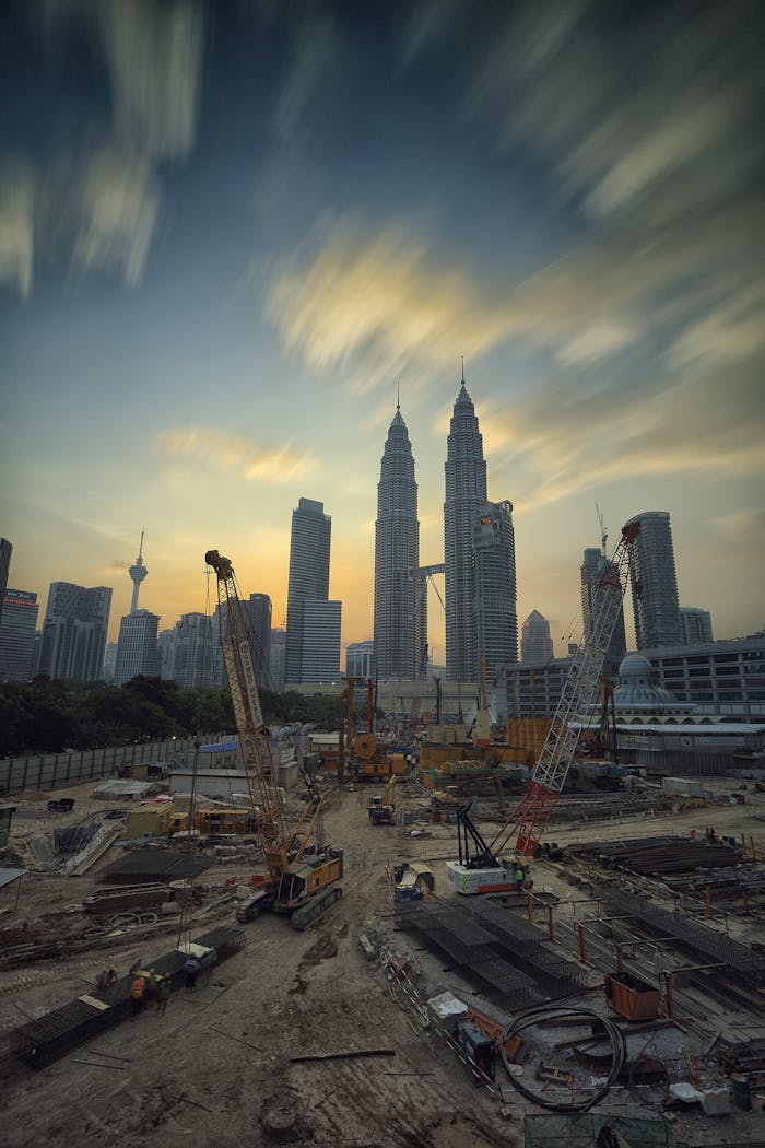 Mastering the First Impression: Your intriguing post title goes here Dramatic view of the Petronas Towers towering over a busy construction site in Kuala Lumpur at sunset.