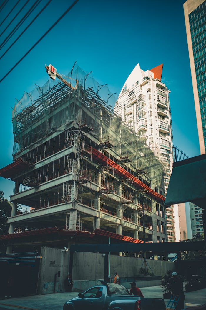 The Art of Drawing Readers In: Your attractive post title goes here High-rise building under construction with scaffolding and crane in urban cityscape.
