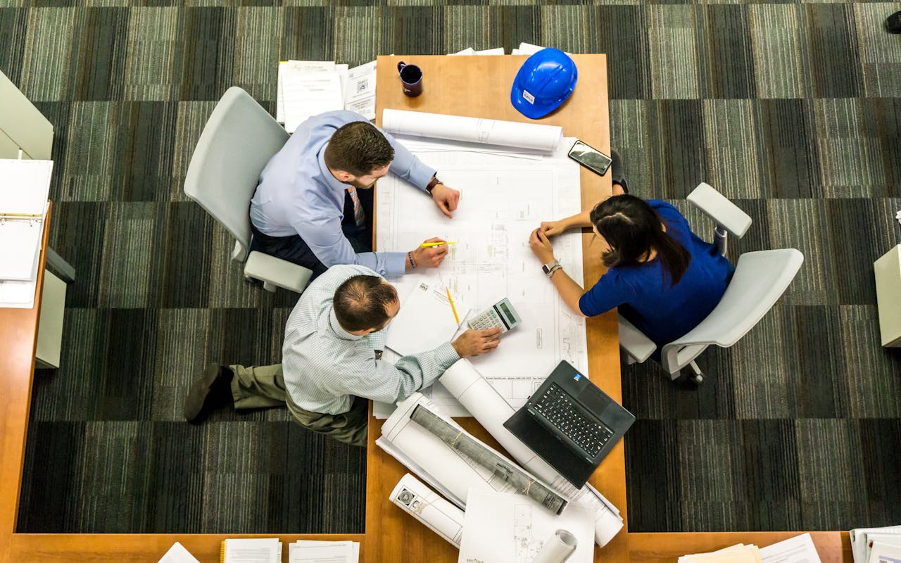 services-06 Top view of a team working on construction plans in an office setting.