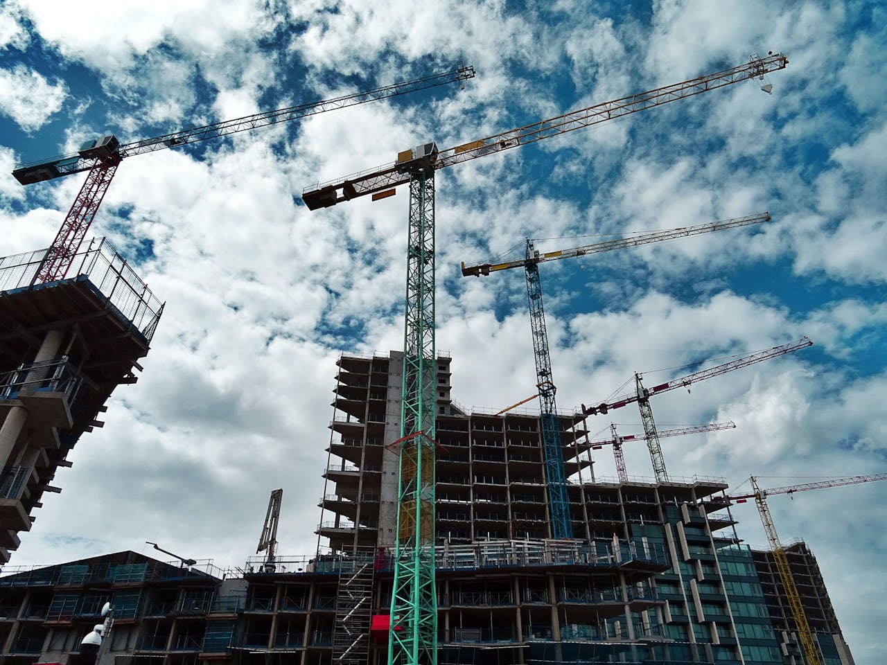 home-hero Urban construction site with numerous cranes framing rising skyscrapers against a blue sky.
